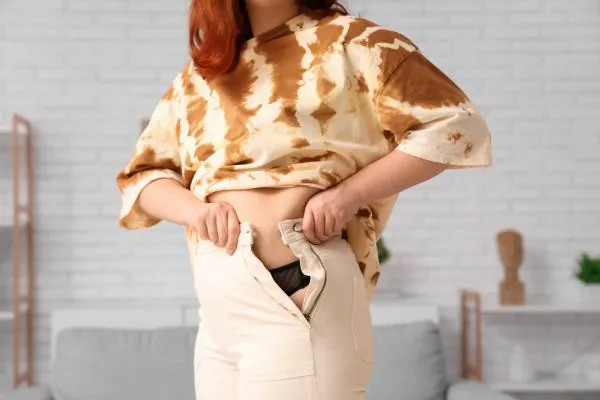 Image of woman trying to do her trousers up after pregnancy weight gain Dunchurch