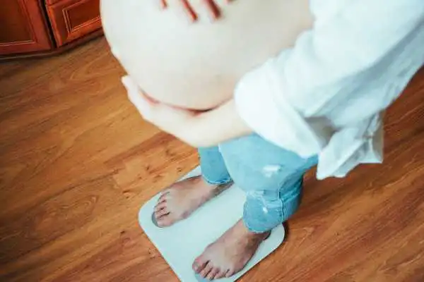 Image of woman weighing herself and experiencing weight gain through pregnancy Dunchurch